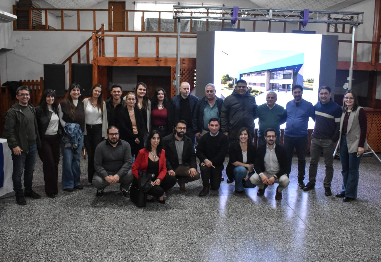 Autoridades municipales y educativas frente a la pantalla con la proyección del nuevo edificio de la Escuela Técnica N.º 1